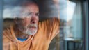 Depressiver Mann lehnt an Fenster