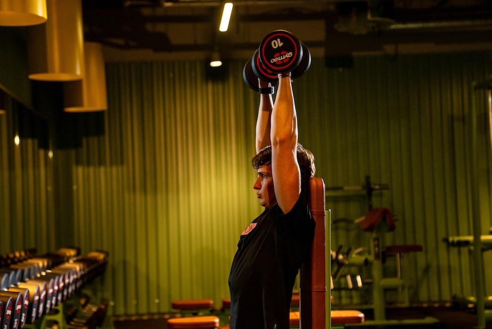 Dr&uuml;cken Sie die Gewichte nicht starr ganz weit au&szlig;en nach oben, sondern lassen Sie die Ellbogen ganz nat&uuml;rlich ein kleines St&uuml;ck (ca. 30 Grad) nach vorne kommen, das schont Ihre Gelenke.