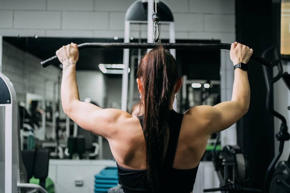 Frau trainiert im Fitnessstudio am Latzug