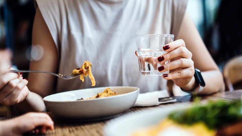 Frau trinkt Wasser zum Essen