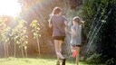 Rasensprenger und Kinder im Garten