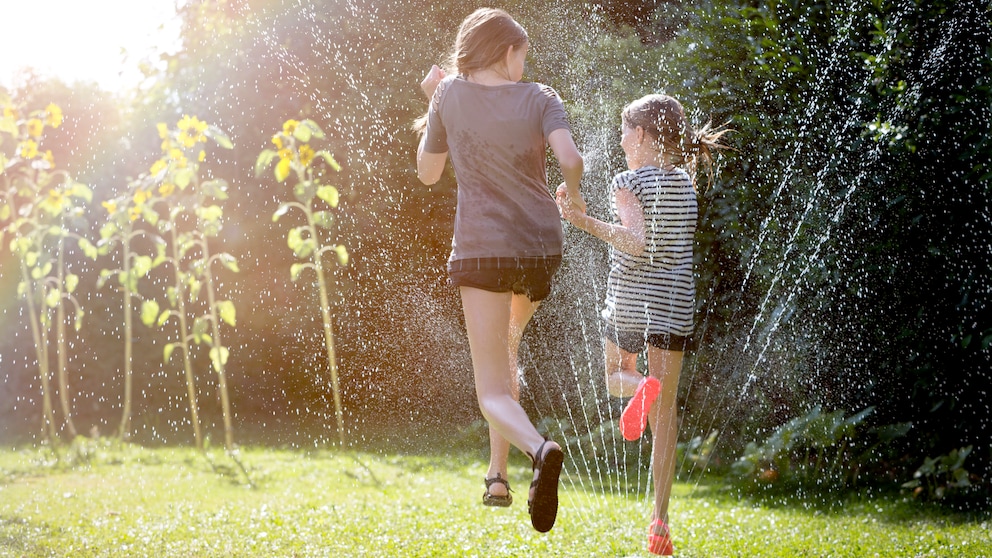 Rasensprenger und Kinder im Garten