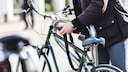 Mann schließt Fahrrad mit Fahrradschloss an.