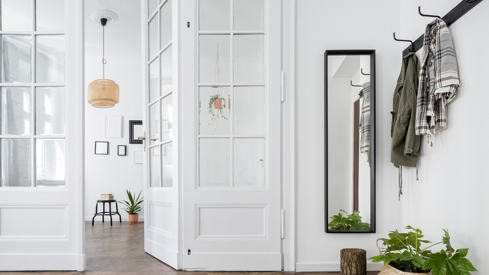 Ein heller Flur mit Garderobe und schmalem Spiegel
