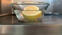 Eine Glasschale mit Wasser und einer halben Zitrone steht in einer Mikrowelle