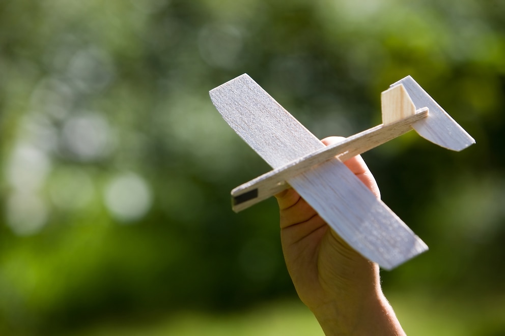 Ein aus Balsaholz gebauter Flieger in der Hand eines Menschen