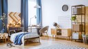Ein Jungendzimmer mit Bett, Schreibtisch am Fenster, einem Teppich und offenen Regalen