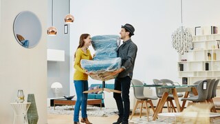 Ein Paar transportiert einen verpackten Stuhl – ob das nachhaltig ist?