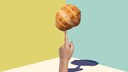 Ein Brot wird auf einem Finger jongliert vor geometrischem Hintergrund