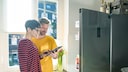 Ein Pärchen steht vor einem modernen Kühlschrank