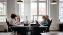 Luftreiniger: Vier Menschen sitzen im Büro mit Mund-Nasen-Schutzmasken