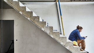 Mann sitzt auf Betontreppe auf Baustelle