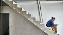 Mann sitzt auf Betontreppe auf Baustelle