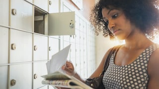 Eine Frau steht vor dem Briefkasten