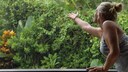 Regen auffangen: Eine Frau streckt die Hand heraus vom Balkon in den Regen