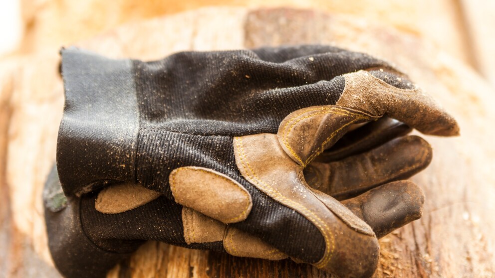 Arbeitshandschuhe liegen auf einem Holzstück