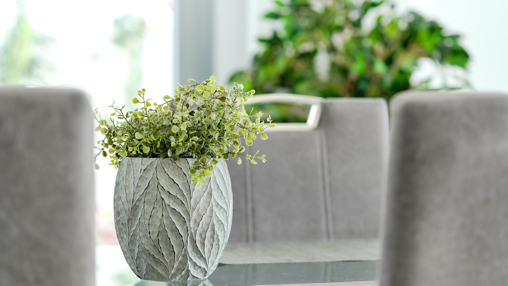 Künstliche Zimmerpflanzen: Eine grüne künstliche Zimmerpflanze in einem grauen Blumentopf
