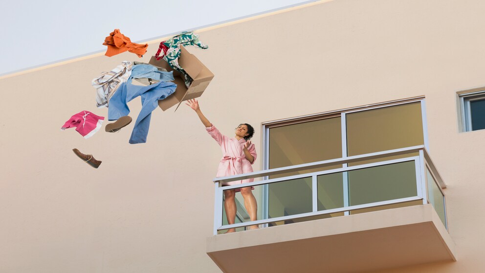 Eine Frau wirft Kleidung aus dem Fenster