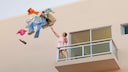 Eine Frau wirft Kleidung aus dem Fenster