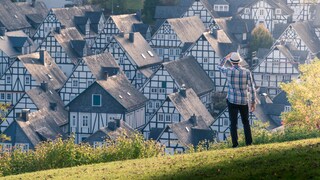 Ein Mann steht auf einem Hügel und schaut auf ein Dorf hinab