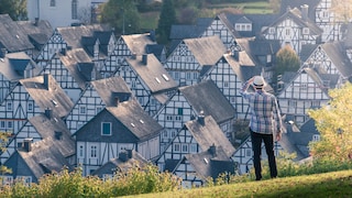 Ein Mann steht auf einem Hügel und schaut auf ein Dorf hinab