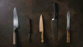 Verschiedene Küchenmesser liegen auf einem dunkeln Untergrund