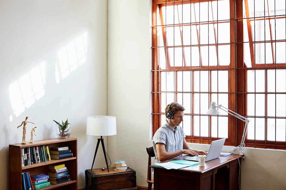 Ein Mann arbeitet am Fenster. Steht der Schreibtisch im rechten Winkel zum Fenster, erhält man die optimale Ausbeute an Tageslicht