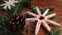 Weihnachtssterne aus Wäscheklammern liegen auf einem Tisch zwischen Tannengrün und Kienäpfeln