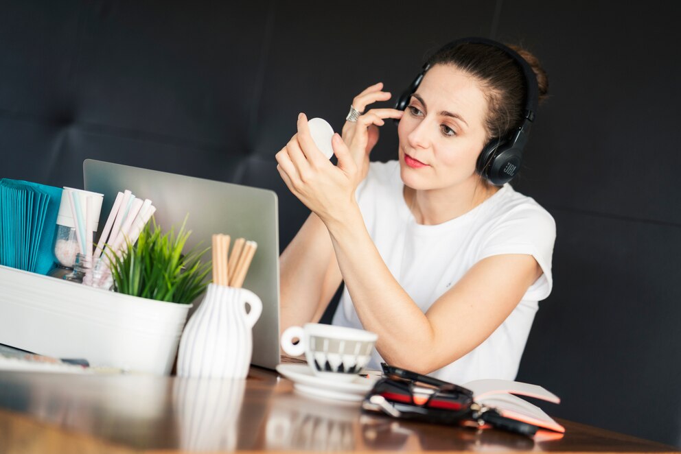 Ein Frau schminkt sich am Arbeitsplatz im Homeoffice