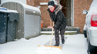 Frau schaufelt Schnee