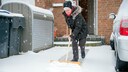 Frau schaufelt Schnee