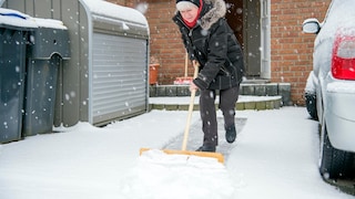 Frau schaufelt Schnee