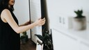 Kunst zu Hause: Eine Frau hängt ein Bild an einer Wand auf