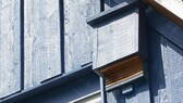 Fledermauskasten: Ein Kasten für Fledermäuse ist an einer Hausfassade aus Holz befestigt