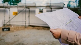 Baunebenkosten: Eine Frau hält einen Bauplan in den Händen