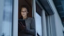 Frau steht in der Balkontür mit einem Tablet in der Hand
