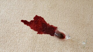 Verschütteter Rotwein auf weißem Teppich