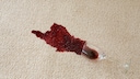 Verschütteter Rotwein auf weißem Teppich