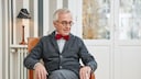 Ein Senior sitzt auf einem Stuhl
