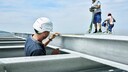 Bauarbeiter arbeiten an dem Stahlgestell eines Dachs