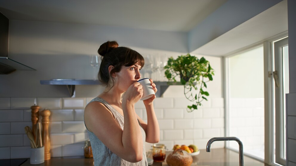 Eine Frau trinkt Kaffee in der Küche