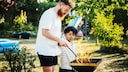Mann und Kind stehen am Grill