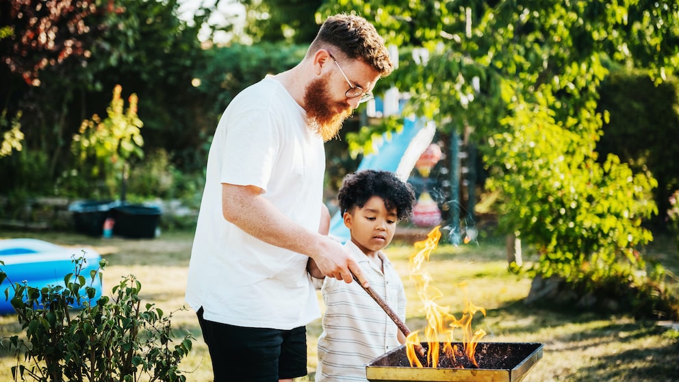 Mann und Kind stehen am Grill