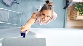 Frau, die fröhlich eine Wand mit Farbe streicht