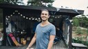 Mann, der eine Kiste trägt und vor einem Schuppen im Garten steht