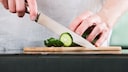 Küchenmesser Qualität: Ein Mann schneidet mit einem Küchenmesser eine Zucchini in Scheiben