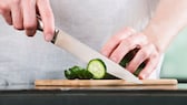 Küchenmesser Qualität: Ein Mann schneidet mit einem Küchenmesser eine Zucchini in Scheiben