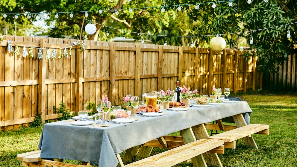 Eine bunt gedeckte Gartentafel mit grauer Tischdecke