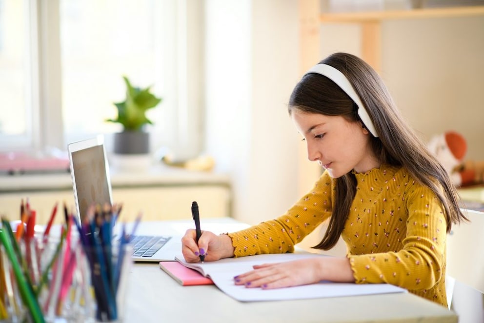 Girl sitting at a desk with a laptop doing homework