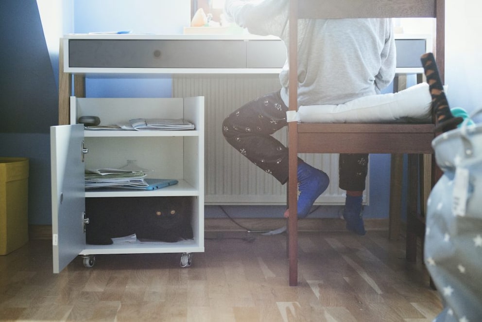 Under a child's desk is a rolling container with open and closed compartments